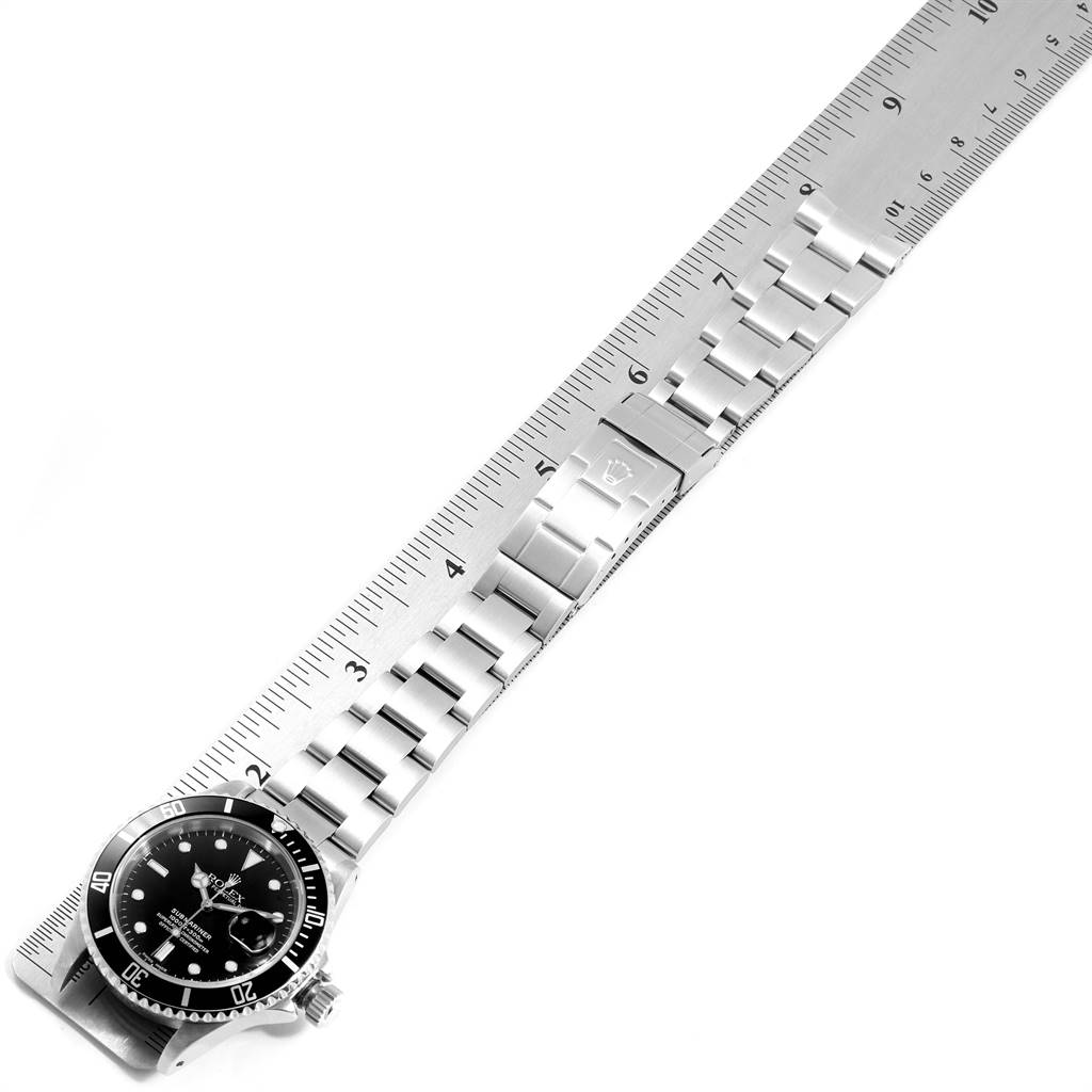 The image shows a Rolex Submariner 16610 Men's Stainless Steel Black Dial 16610 Men's Stainless Steel Black Dial watch laid flat next to a ruler displaying the bracelet and clasp.