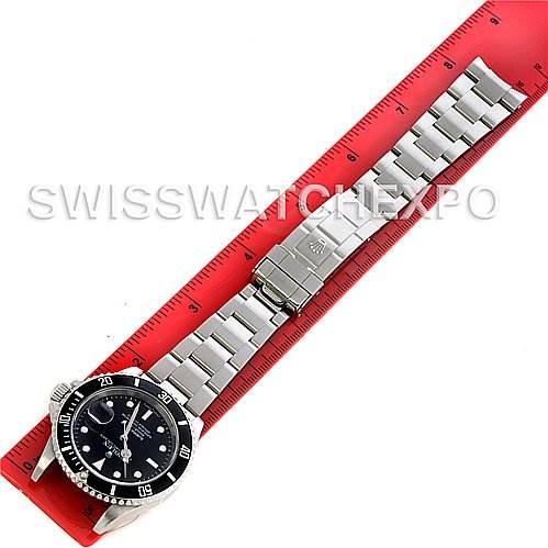 The image shows a Rolex Submariner 16610 Men's Stainless Steel Black Dial 16610 Men's Stainless Steel Black Dial watch laid flat against a red ruler, displaying the entire bracelet, clasp, and dial from a top-down view.