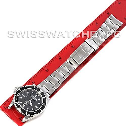The image shows a Rolex Submariner 16610 Men's Stainless Steel Black Dial 16610 Men's Stainless Steel Black Dial watch lying flat with its stainless steel bracelet fully extended along a red ruler.