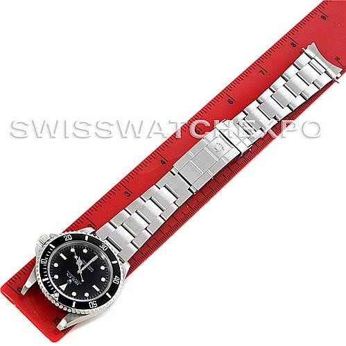 The image shows a top-down view of a Rolex Submariner 14060M Men
s Stainless Steel Black Dial 14060M Men
s Stainless Steel Black Dial watch with its full metal bracelet against a red ruler.