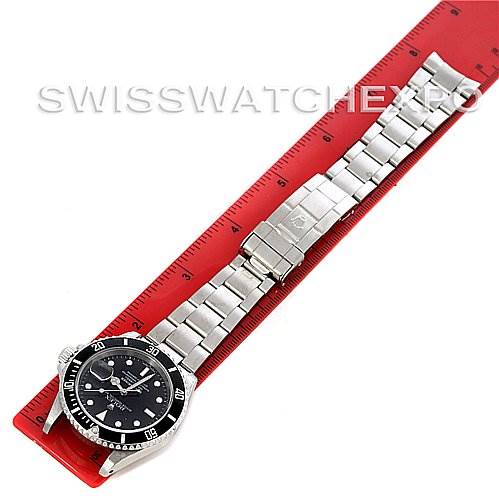 The image depicts a Rolex Submariner 16610 Men's Stainless Steel Black Dial 16610 Men's Stainless Steel Black Dial watch lying flat with its bracelet extended next to a red ruler.