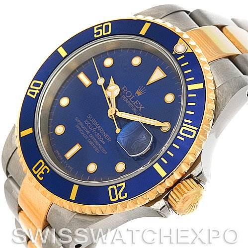 The image shows a Rolex Submariner 16613 Men's Steel and Gold (two tone) Blue Dial 16613 Men's Steel and Gold (two tone) Blue Dial watch at an angle highlighting the blue dial, gold bezel, and metal bracelet.