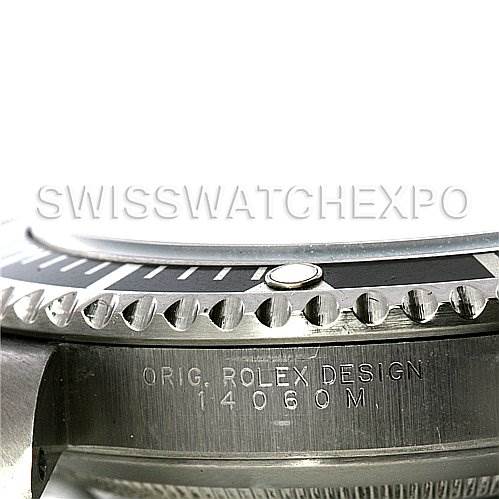 The image shows a close-up side view of a Rolex Submariner 14060M Men's Stainless Steel Black Dial 14060M Men's Stainless Steel Black Dial watch, focusing on the bezel and case with engraved text.
