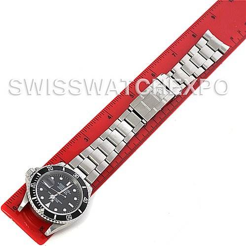 The image shows the entire Rolex Submariner 16610 Men's Stainless Steel Black Dial 16610 Men's Stainless Steel Black Dial watch laid flat next to a red ruler, displaying the watch face, bezel, and bracelet.