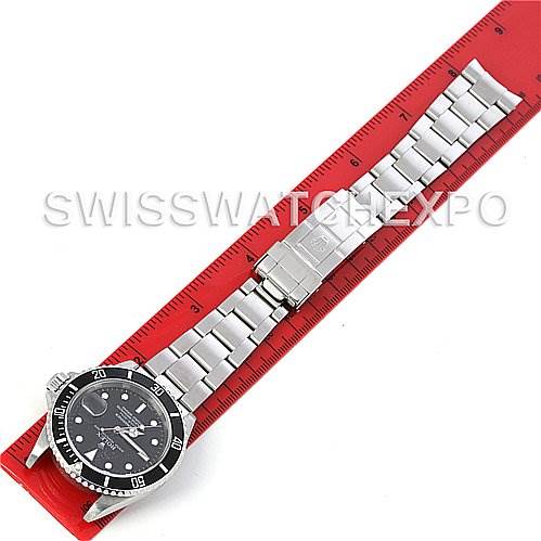 The image shows a top-down view of a Rolex Submariner 16610 Men's Stainless Steel Black Dial 16610 Men's Stainless Steel Black Dial watch laid next to a red ruler.