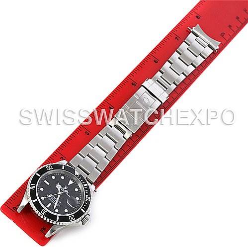 The Rolex Submariner 16610 Men's Stainless Steel Black Dial 16610 Men's Stainless Steel Black Dial watch is shown laid flat on a ruler, displaying the face, bezel, and metal bracelet.