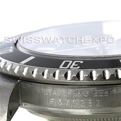 This close-up image of the Rolex Submariner 16610 Men's Stainless Steel Black Dial 16610 Men's Stainless Steel Black Dial shows the bezel, crystal, and case side with engraved text.