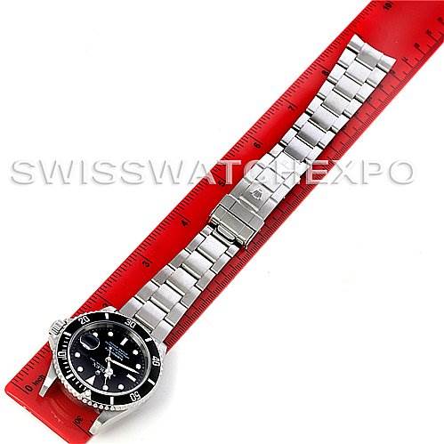 The image shows a top-down view of a Rolex Submariner 16610 Men's Stainless Steel Black Dial 16610 Men's Stainless Steel Black Dial watch, including its black dial, bezel, and metal bracelet, placed next to a red ruler.