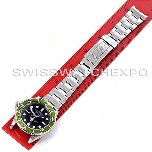 The image shows a full view of a Rolex Submariner 16610LV Men
s Stainless Steel Black Dial 16610LV Men
s Stainless Steel Black Dial watch lying flat, displaying the band and face on a red ruler.