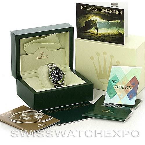 The image shows a Rolex Submariner 16610LV Men
s Stainless Steel Black Dial 16610LV Men
s Stainless Steel Black Dial watch in its open box with accompanying manuals, a warranty card, and a polishing cloth.