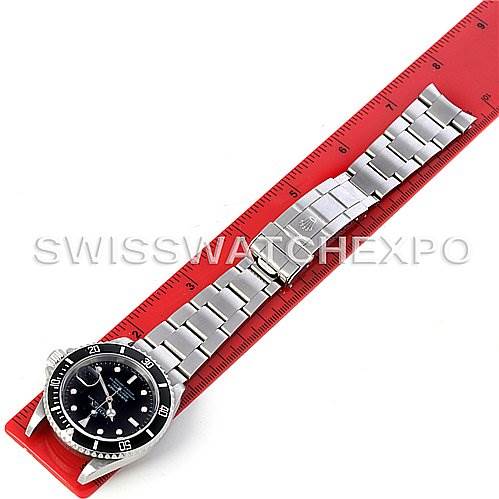 The image shows a top-down view of a Rolex Submariner 16610 Men's Stainless Steel Black Dial 16610 Men's Stainless Steel Black Dial watch placed next to a red measuring ruler.