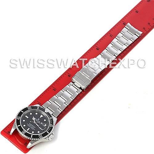 The Rolex Submariner 16610 Men's Stainless Steel Black Dial 16610 Men's Stainless Steel Black Dial watch is shown laid flat next to a red ruler, displaying the full bracelet and face from a top-down angle.