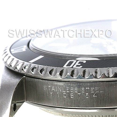 This image shows a close-up side view of the Rolex Submariner 14060M Men's Stainless Steel Black Dial 14060M Men's Stainless Steel Black Dial's bezel, part of the crystal, and case with an engraving.