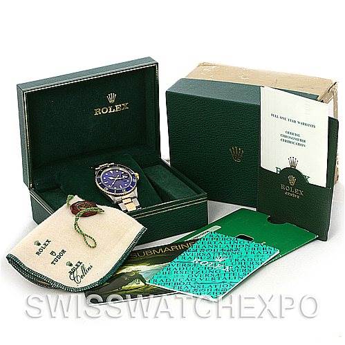 The image shows a Rolex Submariner 16803 Men's Steel and Gold (two tone) Blue Dial 16803 Men's Steel and Gold (two tone) Blue Dial watch at an angle inside its box, alongside its outer box, pouch, and documentation.