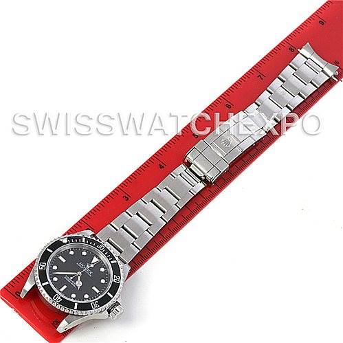 The image shows a Rolex Submariner 14060M Men's Stainless Steel Black Dial 14060M Men's Stainless Steel Black Dial watch laid flat with its bracelet fully extended alongside a red ruler for scale.