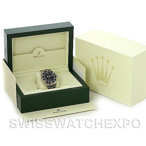 The image shows a Rolex Submariner 14060M Men's Stainless Steel Black Dial 14060M Men's Stainless Steel Black Dial watch at an angled view, placed inside its open green and beige box.