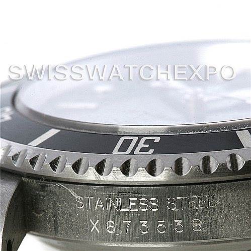 The image shows a close-up of the bezel, crystal, and part of the case of the Rolex Submariner 14060M Men's Stainless Steel Black Dial 14060M Men's Stainless Steel Black Dial watch, highlighting "Stainless Steel" and a serial number.