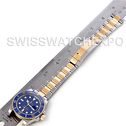 The Rolex Submariner 116613BLSO Men's Steel and Gold (two tone) Blue Dial 116613BLSO Men's Steel and Gold (two tone) Blue Dial watch is shown laid flat next to a ruler, highlighting its full bracelet and dial.
