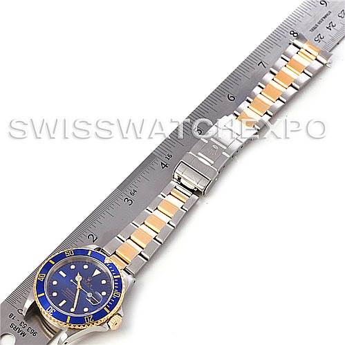 The image shows a blue and gold Rolex Submariner 16613 Men's Steel and Gold (two tone) Blue Dial 16613 Men's Steel and Gold (two tone) Blue Dial watch laid flat next to a ruler, displaying its full bracelet and face.