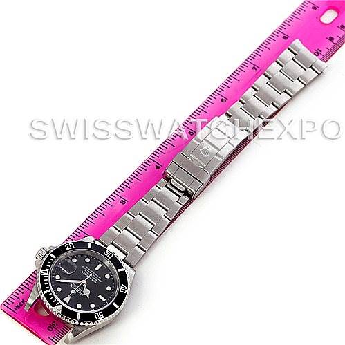 The image shows a top-down view of a Rolex Submariner 16610 Men's Stainless Steel Black Dial 16610 Men's Stainless Steel Black Dial watch with a metal bracelet, next to a pink ruler.