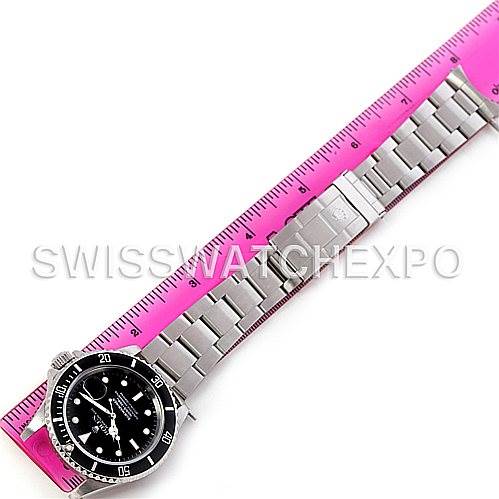 The image shows a Rolex Submariner 16610 Men's Stainless Steel Black Dial 16610 Men's Stainless Steel Black Dial watch laid flat beside a pink ruler, highlighting the stainless steel bracelet and black dial.