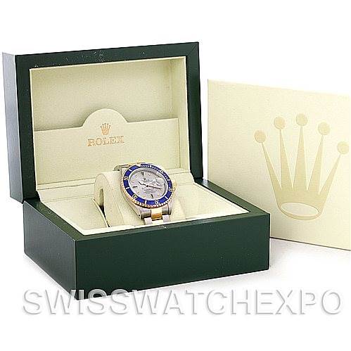 The image shows a Rolex Submariner 16613 Men's Steel and Gold (two tone) Grey Dial 16613 Men's Steel and Gold (two tone) Grey Dial watch displayed at an angle, within its open box, with the brand's logo visible on the packaging.