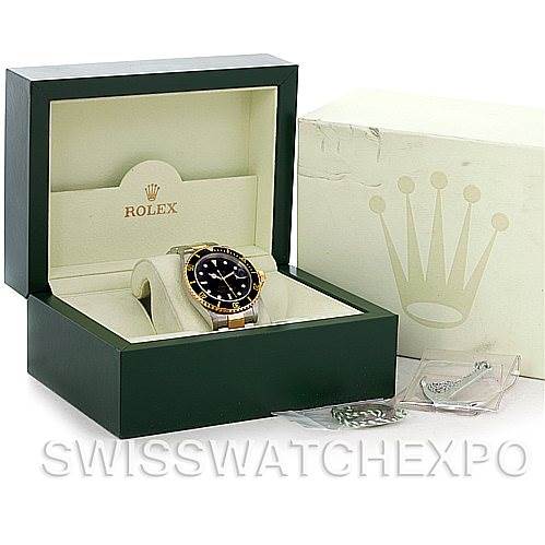 This image shows a Rolex Submariner 16613 Men's Steel and Gold (two tone) Black Dial 16613 Men's Steel and Gold (two tone) Black Dial watch at a slight left angle, in an open green box with extra links and a white outer box.