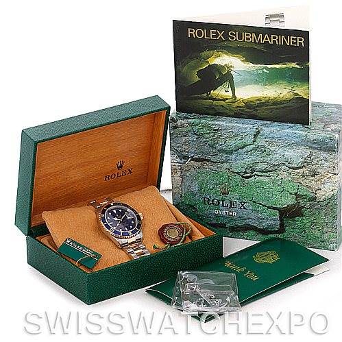 This image shows a Rolex Submariner 16613 Men's Steel and Gold (two tone) Blue Dial 16613 Men's Steel and Gold (two tone) Blue Dial watch with its original packaging, instruction manual, and warranty card in an open display.