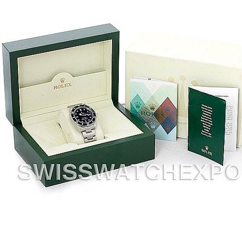 The image shows a Rolex Submariner 16610 Men
s Stainless Steel Black Dial 16610 Men
s Stainless Steel Black Dial watch in its open green box, along with its accompanying booklets and documents.