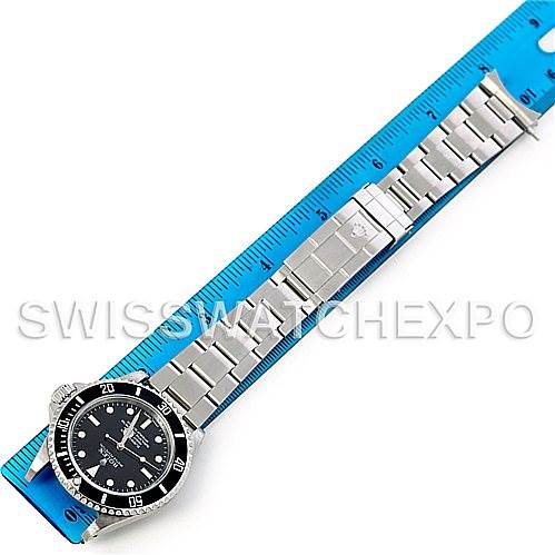 This top-down image shows the entire Rolex Submariner 14060 Men's Stainless Steel Black Dial 14060 Men's Stainless Steel Black Dial watch, including the watch face, bezel, and bracelet, lying next to a blue ruler.