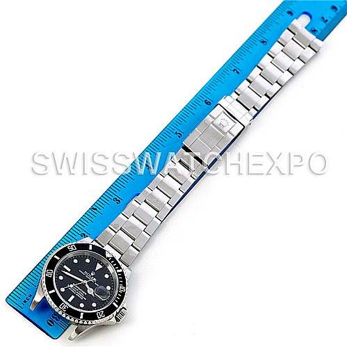 This image shows the top view of a Rolex Submariner 16610 Men's Stainless Steel Black Dial 16610 Men's Stainless Steel Black Dial watch fully extended alongside a blue ruler.