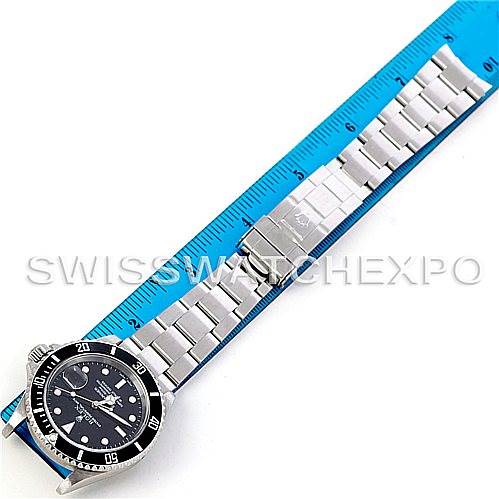 The image shows a Rolex Submariner 16610 Men's Stainless Steel Black Dial 16610 Men's Stainless Steel Black Dial watch laid flat next to a ruler, displaying its stainless steel bracelet and black dial.