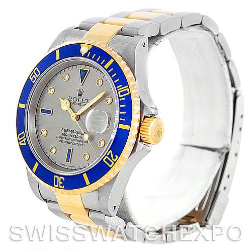The image shows a Rolex Submariner 16613 Men's Steel and Gold (two tone) Grey Dial 16613 Men's Steel and Gold (two tone) Grey Dial watch from a right-front angle, highlighting the blue and gold bezel, dial, and two-tone bracelet.