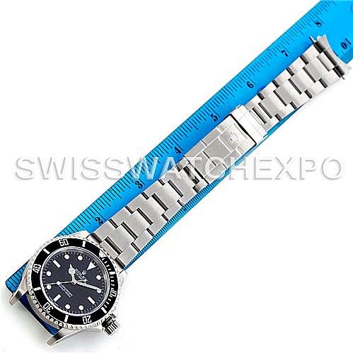 The image shows a full view of a Rolex Submariner 14060 Men's Stainless Steel Black Dial 14060 Men's Stainless Steel Black Dial watch lying next to a ruler, displaying its dial, bezel, and metal bracelet.