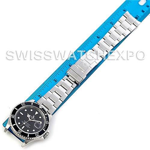 The image shows a top-down view of a Rolex Submariner 16610 Men
s Stainless Steel Black Dial 16610 Men
s Stainless Steel Black Dial watch with its stainless steel bracelet laid along a blue measuring ruler.