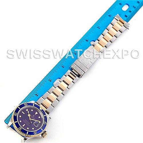 The Rolex Submariner 16613 Men's Steel and Gold (two tone) Blue Dial 16613 Men's Steel and Gold (two tone) Blue Dial watch is shown laid flat next to a blue ruler, displaying the face, bezel, and bracelet.