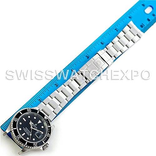 The Rolex Submariner 16610 Men
s Stainless Steel Black Dial 16610 Men
s Stainless Steel Black Dial watch is shown laid flat with its stainless steel bracelet extended and measured against a blue ruler.