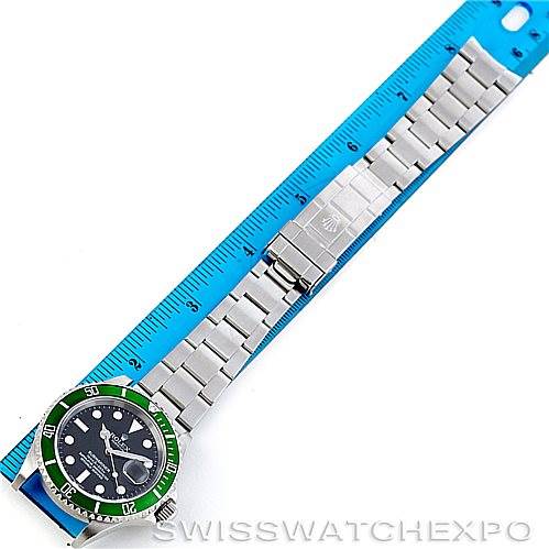 The image shows the Rolex Submariner 16610LV Men
s Stainless Steel Black Dial 16610LV Men
s Stainless Steel Black Dial watch laid flat next to a ruler, displaying its stainless steel bracelet and green bezel.