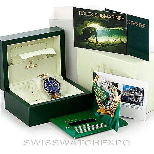 The image shows a Rolex Submariner 16613 Men's Steel and Gold (two tone) Blue Dial 16613 Men's Steel and Gold (two tone) Blue Dial watch in its open box, with accompanying booklets and packaging in the background.