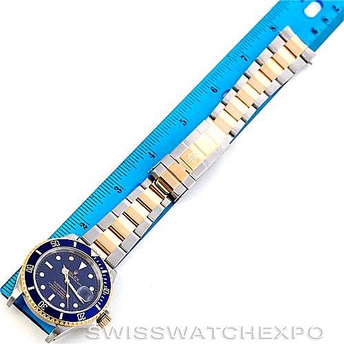 The Rolex Submariner 16613 Men's Steel and Gold (two tone) Blue Dial 16613 Men's Steel and Gold (two tone) Blue Dial watch is displayed flat with a ruler for scale, showing the full band and dial from an overhead angle.
