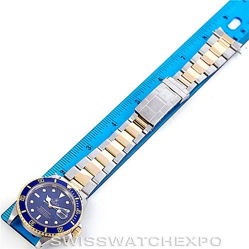 This image shows a Rolex Submariner 16613 Men's Steel and Gold (two tone) Blue Dial 16613 Men's Steel and Gold (two tone) Blue Dial watch with a blue dial and bezel, placed along a blue ruler for size reference.