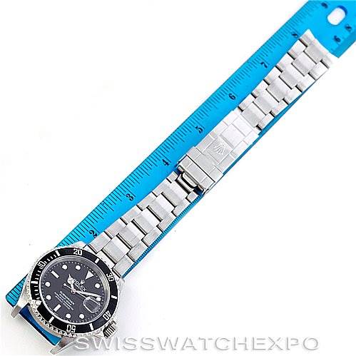 The image shows a top-down view of a Rolex Submariner 16610 Men
s Stainless Steel Black Dial 16610 Men
s Stainless Steel Black Dial watch laid out next to a blue ruler for measurement.