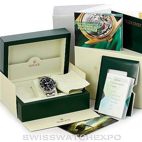 The image shows a Rolex Submariner 16610 Men
s Stainless Steel Black Dial 16610 Men
s Stainless Steel Black Dial in its box, accompanied by various booklets and a cleaning cloth.