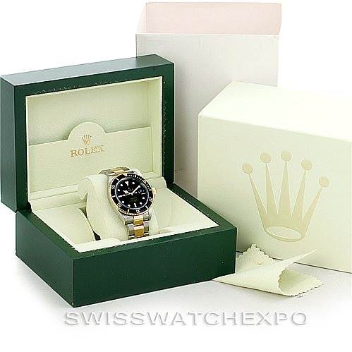 The image shows a Rolex Submariner 16613 Men's Steel and Gold (two tone) Black Dial 16613 Men's Steel and Gold (two tone) Black Dial watch inside its green display box, with the outer box and a cleaning cloth beside it.