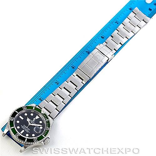 This image shows a Rolex Submariner 16610T Men
s Stainless Steel Black Dial 16610T Men
s Stainless Steel Black Dial watch laid flat with its bracelet fully extended next to a ruler measuring its length.