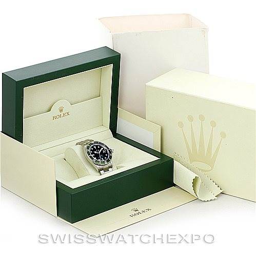 The image shows a Rolex Submariner 16610T Men
s Stainless Steel Black Dial 16610T Men
s Stainless Steel Black Dial watch at an angle inside its open green box, with the outer box and accessories visible.