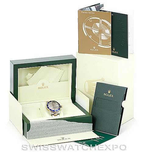 This image shows a Rolex Submariner 16613 Men's Steel and Gold (two tone) Grey Dial 16613 Men's Steel and Gold (two tone) Grey Dial watch in its box, with accompanying manuals and a polishing cloth displayed around it.