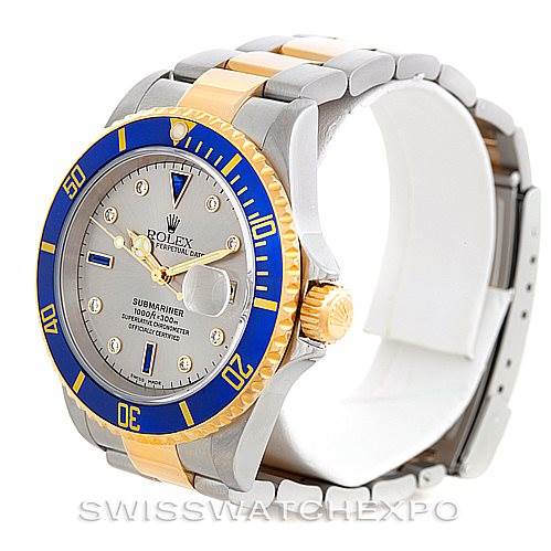 The Rolex Submariner 16613 Men's Steel and Gold (two tone) Grey Dial 16613 Men's Steel and Gold (two tone) Grey Dial watch is shown at a three-quarter angle, displaying the face, bezel, crown, and part of the bracelet.