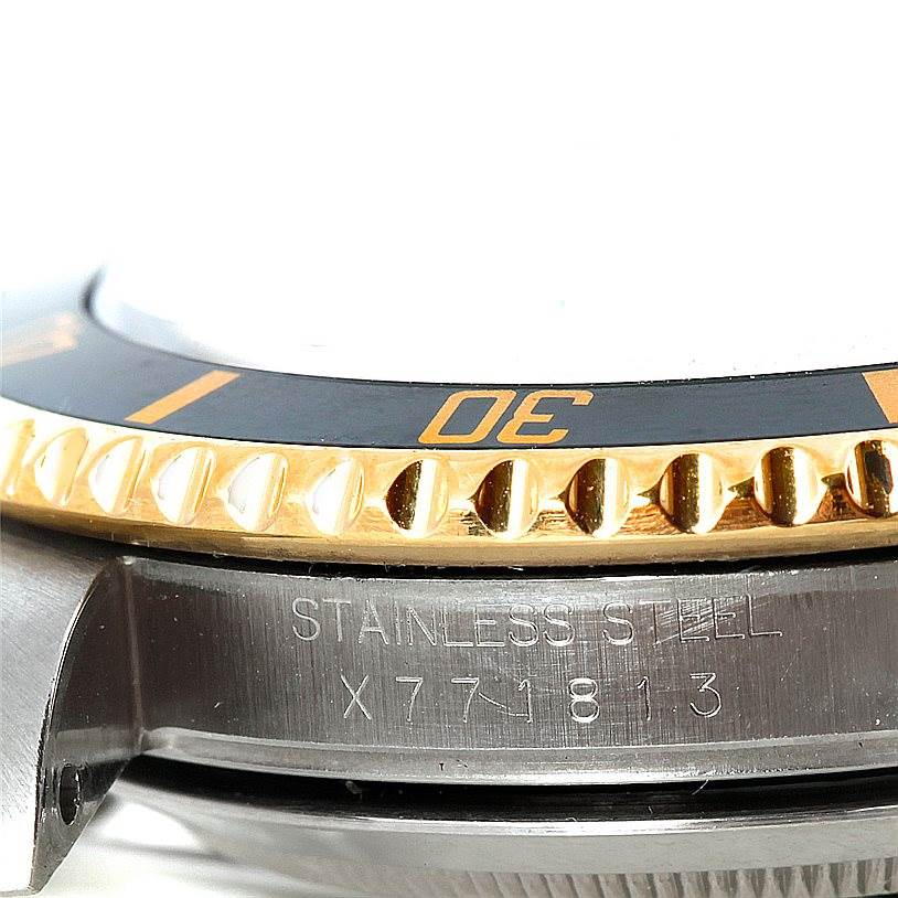 This image shows a close-up angle of a Rolex Submariner 16613 Men's Steel and Gold (two tone) Black Dial 16613 Men's Steel and Gold (two tone) Black Dial's stainless steel case, with part of the bezel and serial number visible.
