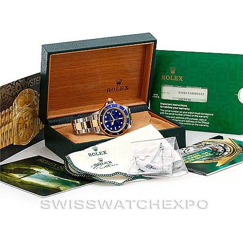 The image shows a Rolex Submariner 16613 Men's Steel and Gold (two tone) Blue Dial 16613 Men's Steel and Gold (two tone) Blue Dial watch in its open box, alongside various accessories, manuals, and guarantee cards.